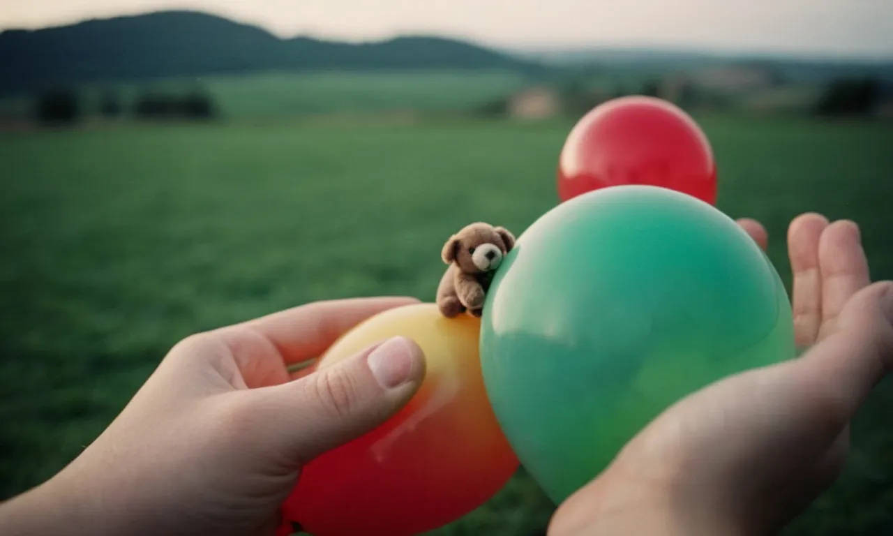 A close-up shot captures the delicate hands of a person gently guiding a small stuffed animal into a partially inflated balloon, creating a whimsical and unique display of creativity.